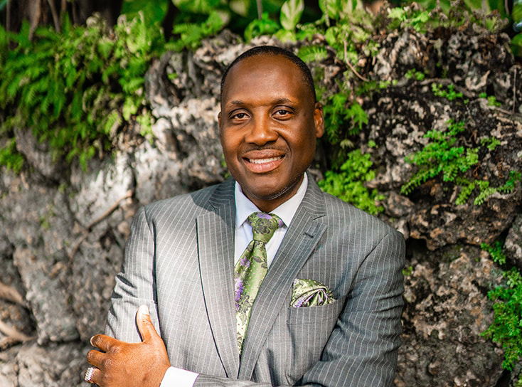 A man wearing a suit and tie standing outside.